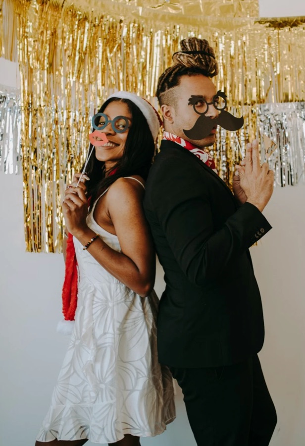 Pareja espalda con espalda con lentes y bigote de props frente a una cortina dorada
