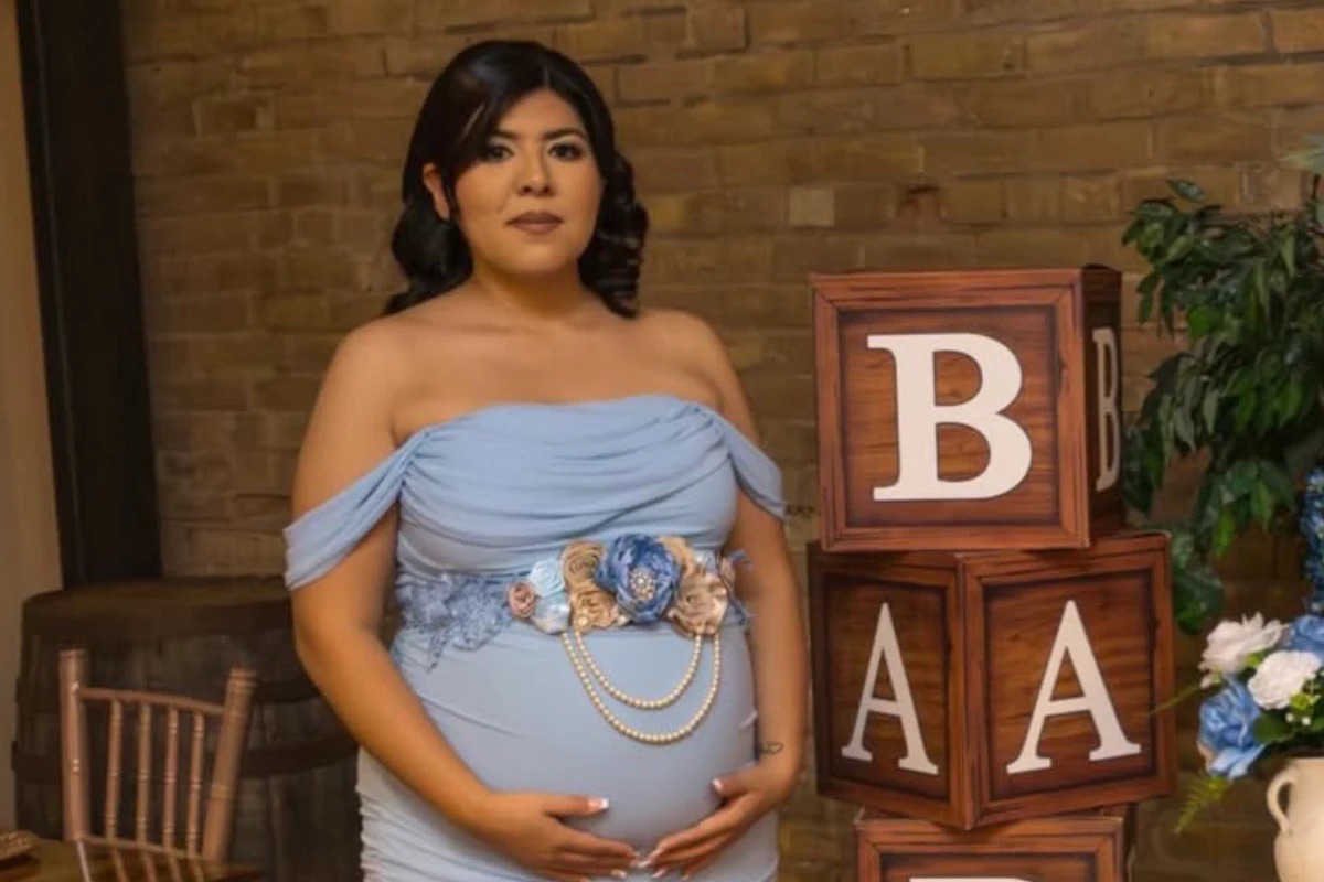 Futura mamá con vestido azul junto a los bloques de BABY en su baby shower